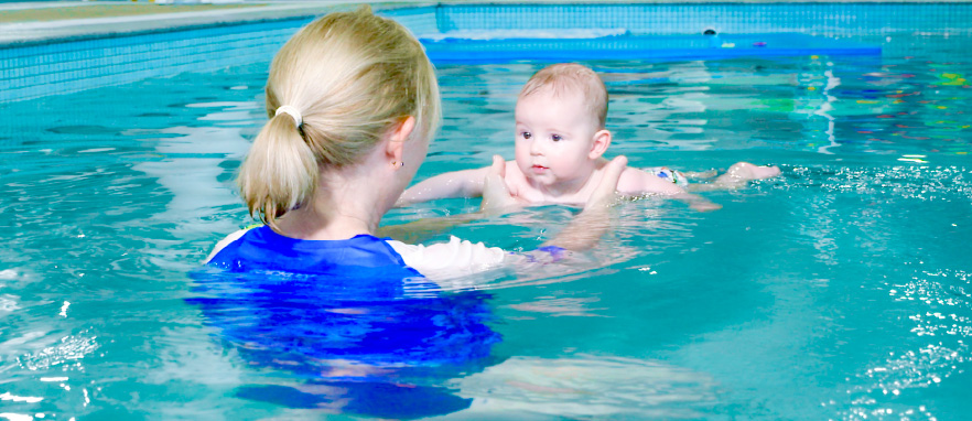 woman helping baby float in pool