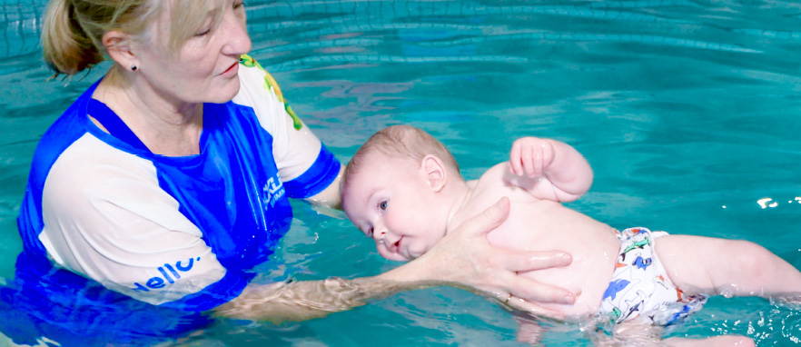 woman rotating baby in pool